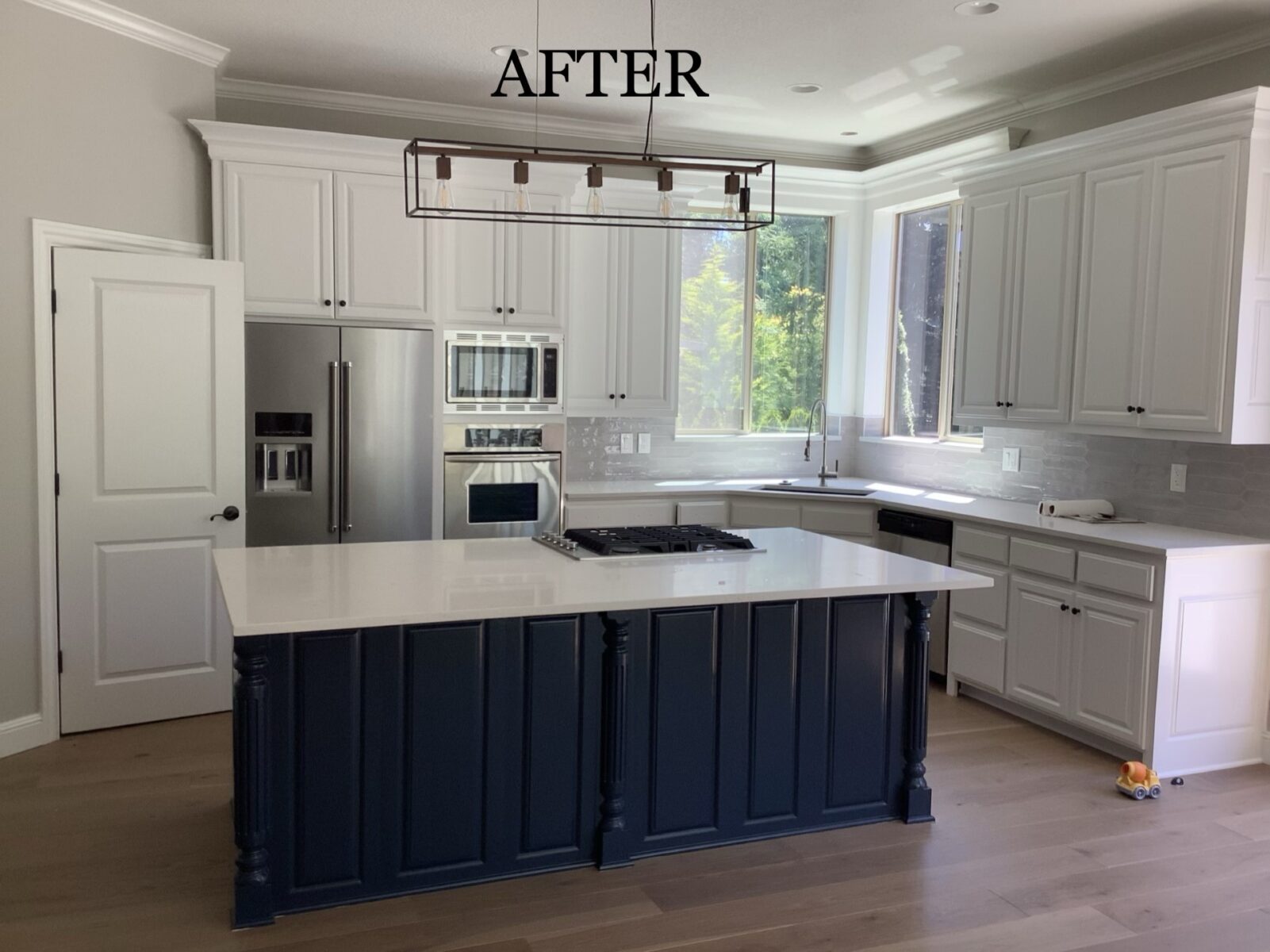 Renovated kitchen with white cabinets, stainless steel appliances, and a blue island.