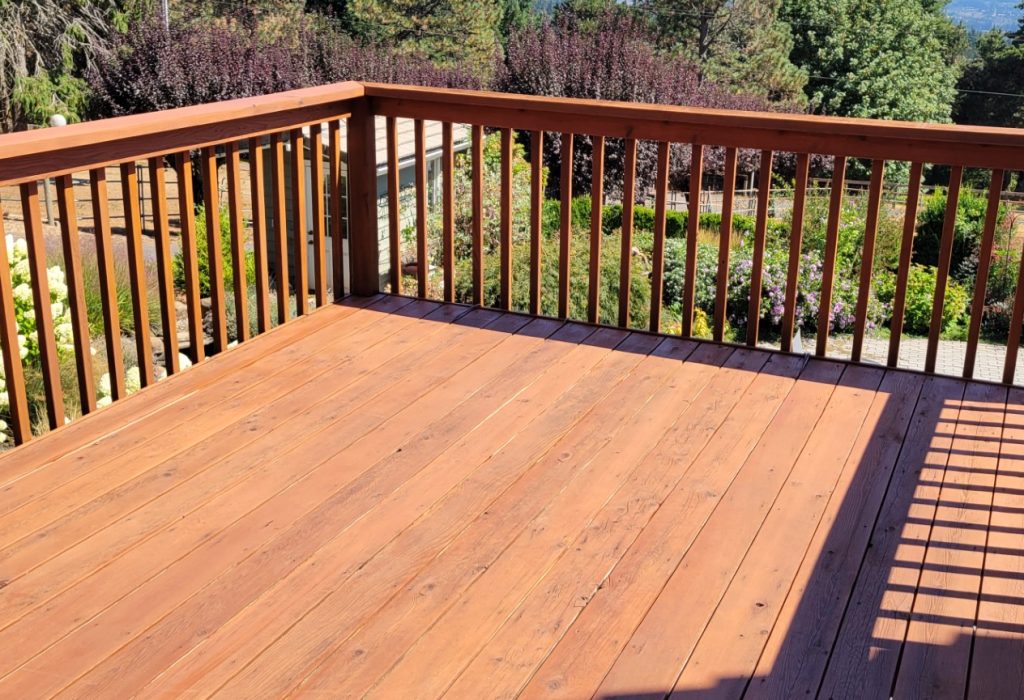 Wooden deck overlooking a garden with a scenic landscape in the background.