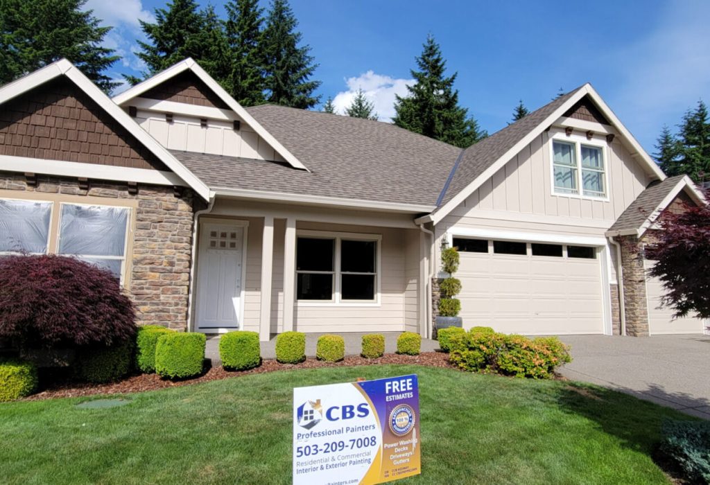 Suburban single-story house with a double garage and landscaped front yard, featuring a real estate sign indicating the property is for sale.